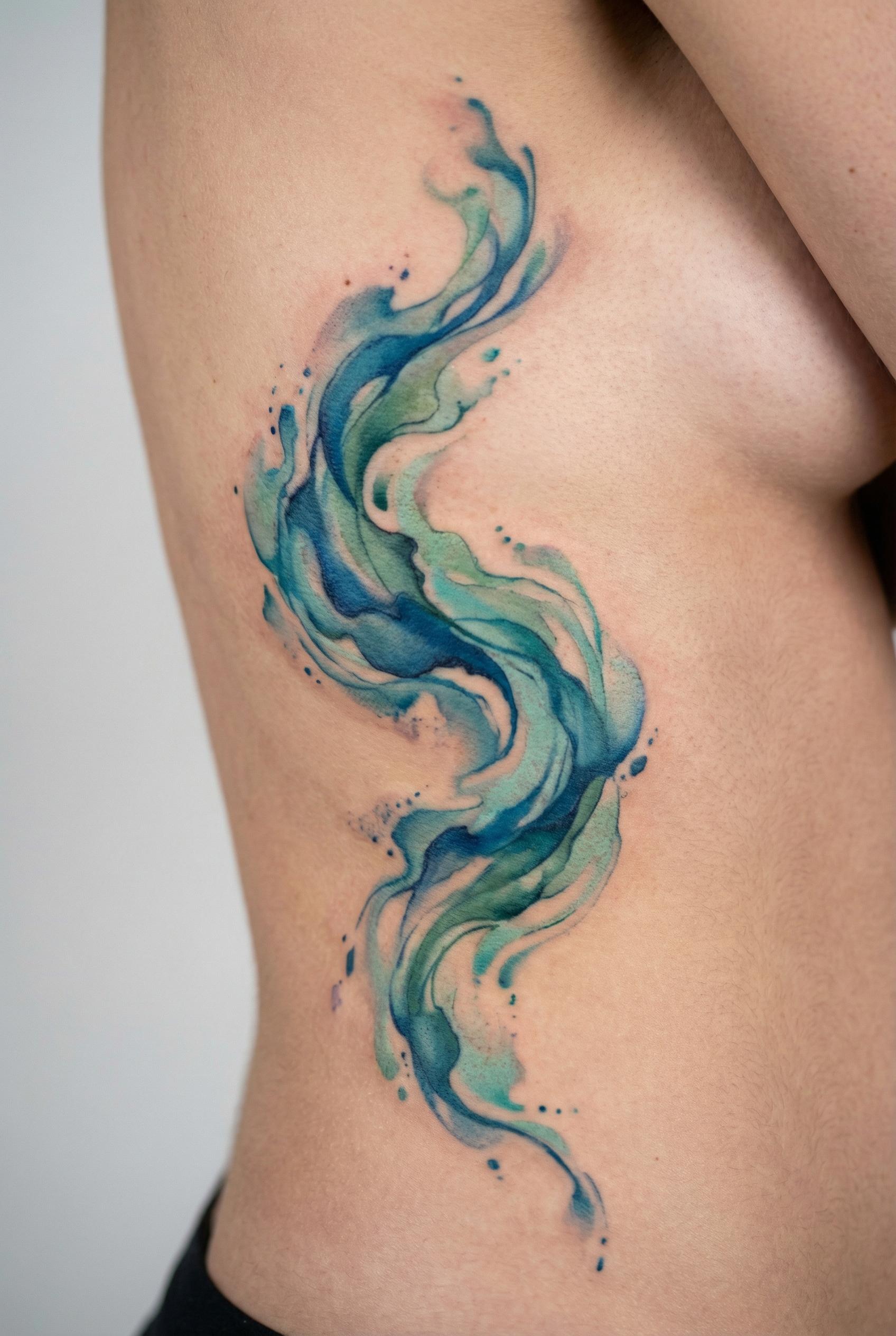 A fluid tattoo design on a woman's ribcage depicting an abstract ocean current rendered entirely in flowing watercolor w