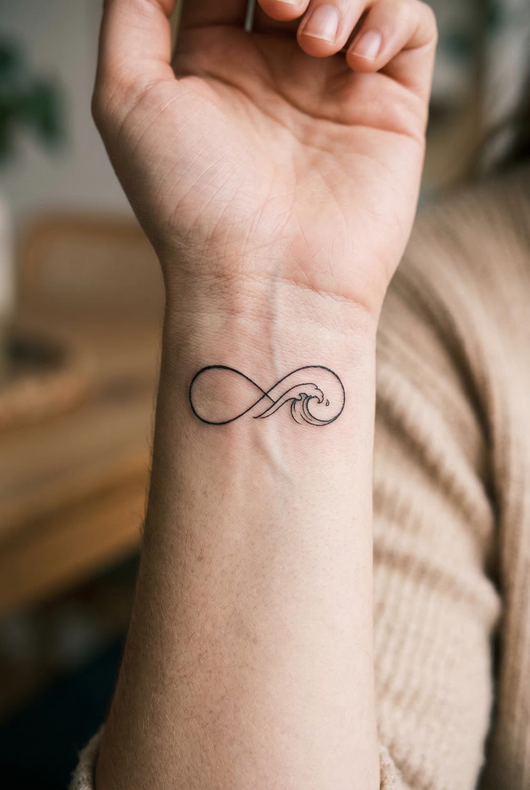 A tiny infinity symbol tattoo on the inner wrist seamlessly intertwined with a small ocean wave, the infinity loop flows
