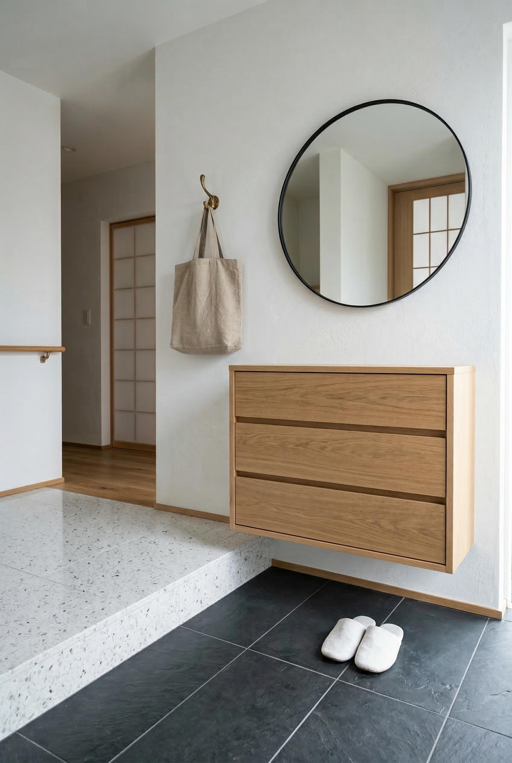 A minimalist Japanese genkan entryway with a floating light oak shoe cabinet mounted to the wall with nothing touching t