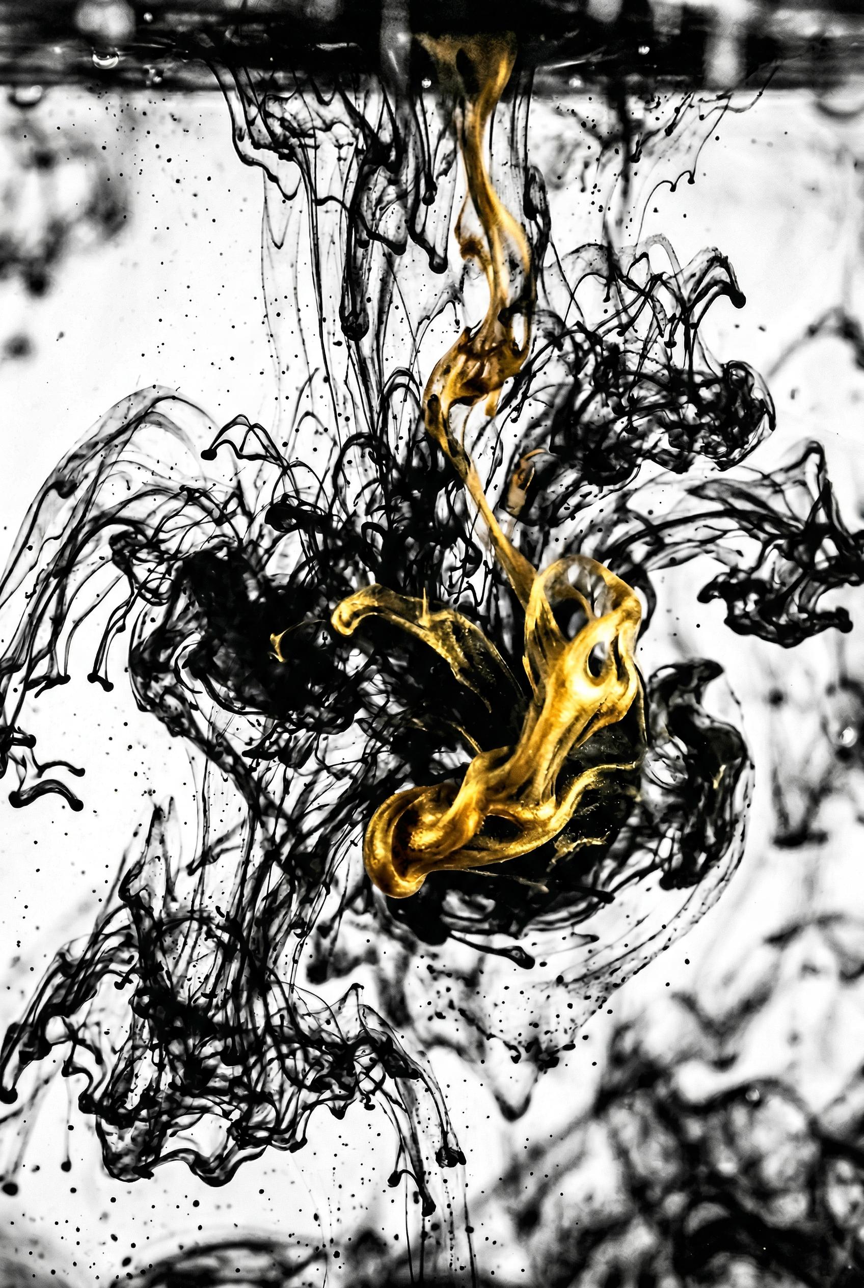 An abstract macro photograph shot from below of ink drops exploding and diffusing in clear water, tendrils and swirling