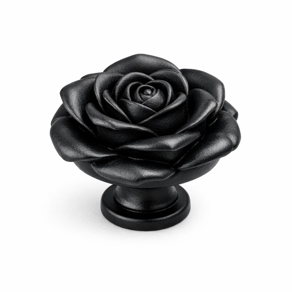 Commercial product photograph. A single residential cabinet knob. Floral surface texture. Round Knob shape. Matte Black metal finish. Small circular base plate, single mounting post, approximately 1-1/4 inch diameter. Photographed on pure white seamless background (#FFFFFF). Studio softbox lighting, soft shadow directly underneath only. Macro lens, sharp focus throughout. Photorealistic real metal hardware. Not a 3D render. Not an illustration. Not CGI. Real cabinet hardware product photography quality. Variation 1: Cabinet knob sculpted entirely in the shape of a single large rose blossom, layered curling petals opening from a center bud, deep three-dimensional undercut petals with clear separation and shadow between them, mounted on a small round base. Cast metal floral hardware..
