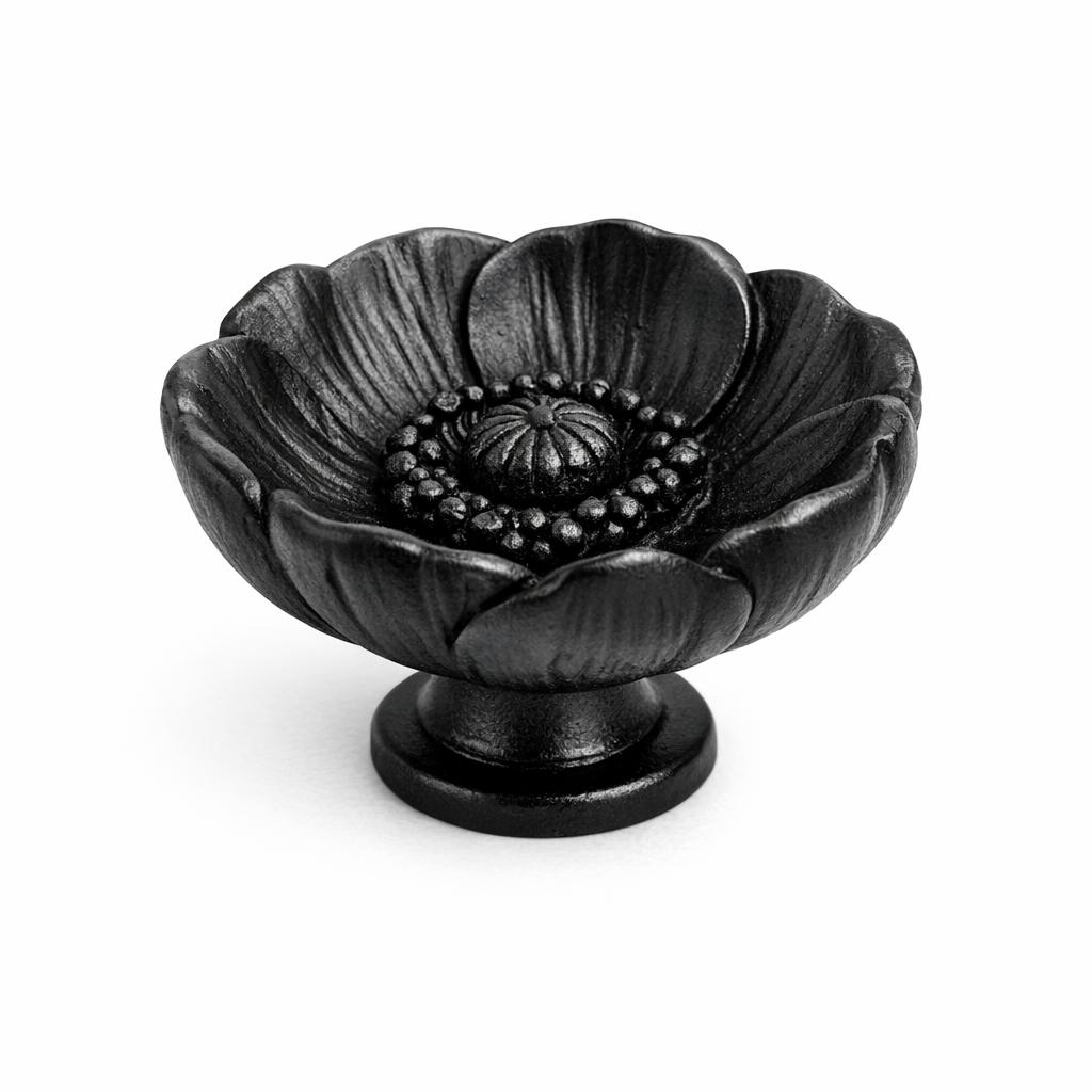 Commercial product photograph. A single residential cabinet knob. Floral surface texture. Round Knob shape. Matte Black metal finish. Small circular base plate, single mounting post, approximately 1-1/4 inch diameter. Photographed on pure white seamless background (#FFFFFF). Studio softbox lighting, soft shadow directly underneath only. Macro lens, sharp focus throughout. Photorealistic real metal hardware. Not a 3D render. Not an illustration. Not CGI. Real cabinet hardware product photography quality. Variation 10: Cabinet knob sculpted as a single poppy bloom, wide cupped rounded petals forming a shallow bowl shape with a dark textured center, dimensional relief, small round base. Cast metal floral hardware..