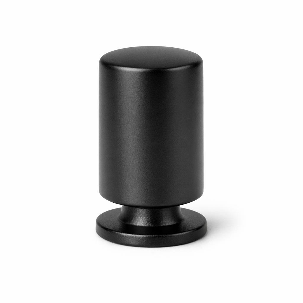 Commercial product photograph. A single residential cabinet knob. Smooth surface texture. Round Knob shape. Matte Black metal finish. Small circular base plate, single mounting post, approximately 1-1/4 inch diameter. Photographed on pure white seamless background (#FFFFFF). Studio softbox lighting, soft shadow directly underneath only. Macro lens, sharp focus throughout. Photorealistic real metal hardware. Not a 3D render. Not an illustration. Not CGI. Real cabinet hardware product photography quality. Variation 6: Freestone style cabinet knob: a tall vertical barrel, an elongated cylinder standing taller than wide with gently rounded top edges and a narrow base. Smooth surface, no texture, no ribbing, no decorative details..