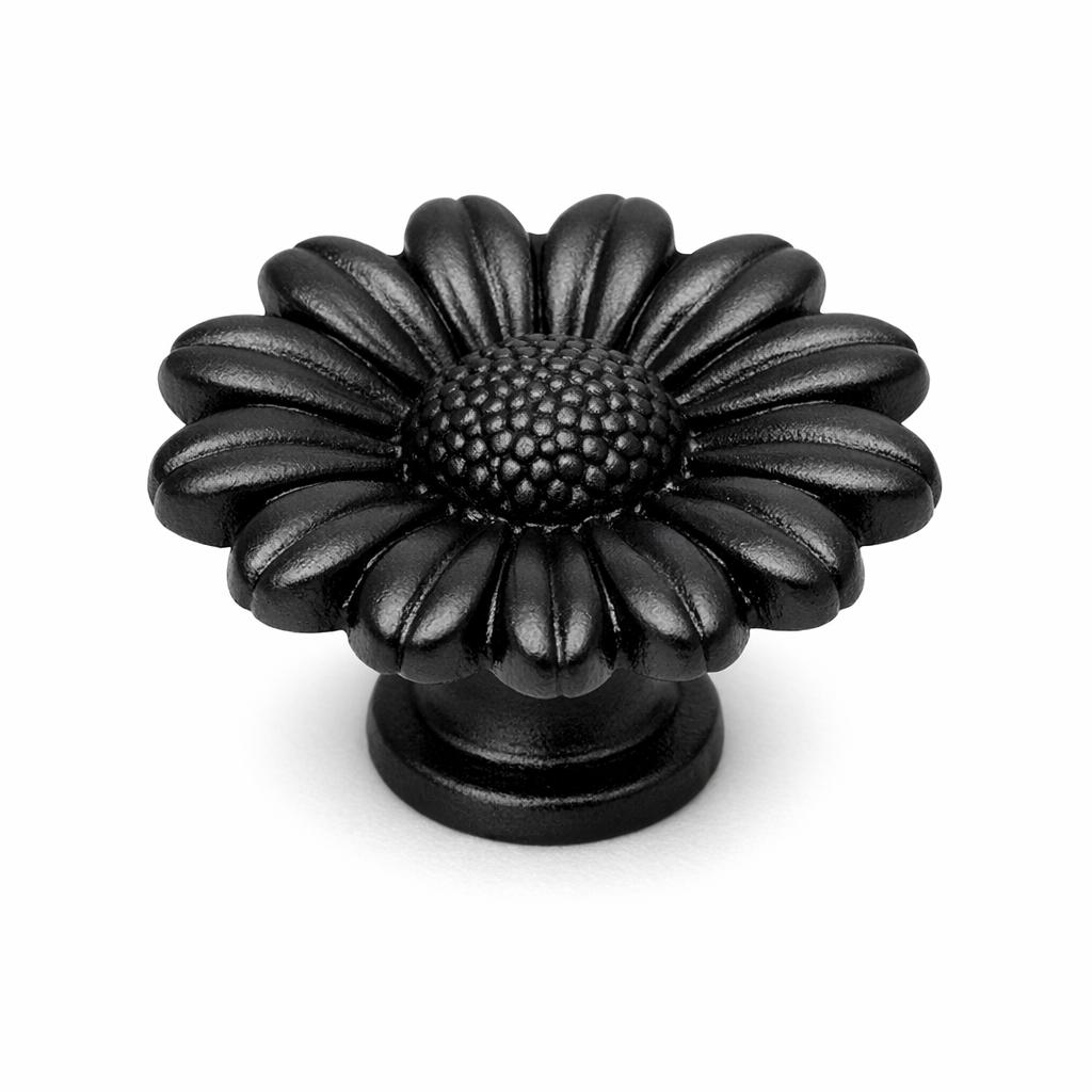 Commercial product photograph. A single residential cabinet knob. Floral surface texture. Round Knob shape. Matte Black metal finish. Small circular base plate, single mounting post, approximately 1-1/4 inch diameter. Photographed on pure white seamless background (#FFFFFF). Studio softbox lighting, soft shadow directly underneath only. Macro lens, sharp focus throughout. Photorealistic real metal hardware. Not a 3D render. Not an illustration. Not CGI. Real cabinet hardware product photography quality. Variation 2: Cabinet knob sculpted as a single flat open daisy flower face, petals radiating outward from a raised textured center disc, deep dimensional petals standing proud with negative space between them, small round base. Cast metal floral hardware..
