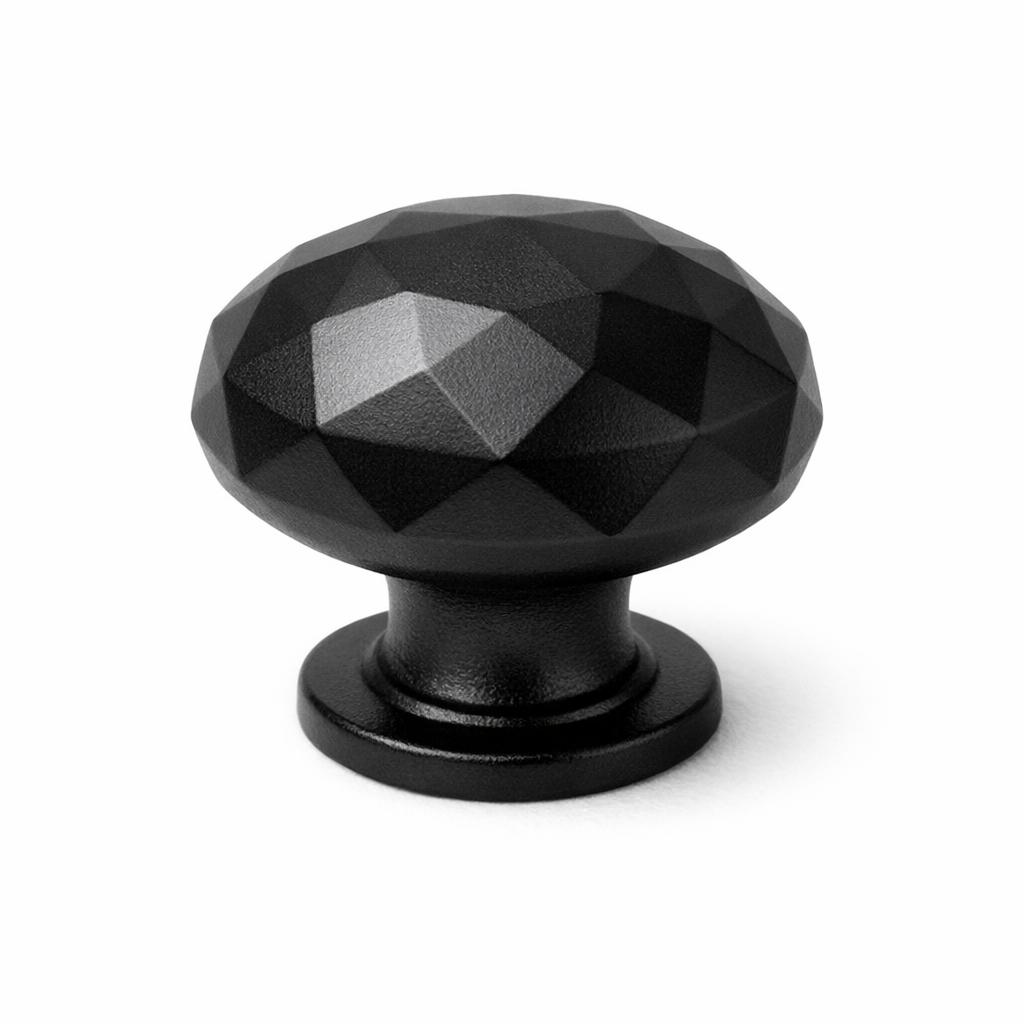 Commercial product photograph. A single residential cabinet knob. Faceted surface texture. Round Knob shape. Matte Black metal finish. Small circular base plate, single mounting post, approximately 1-1/4 inch diameter. Photographed on pure white seamless background (#FFFFFF). Studio softbox lighting, soft shadow directly underneath only. Macro lens, sharp focus throughout. Photorealistic real metal hardware. Not a 3D render. Not an illustration. Not CGI. Real cabinet hardware product photography quality. Variation 1: Providence style cabinet knob: tall mushroom dome cut into flat angular gem-like facets across the entire dome, sharp-edged planes catching light, short thick neck, small circular base plate..