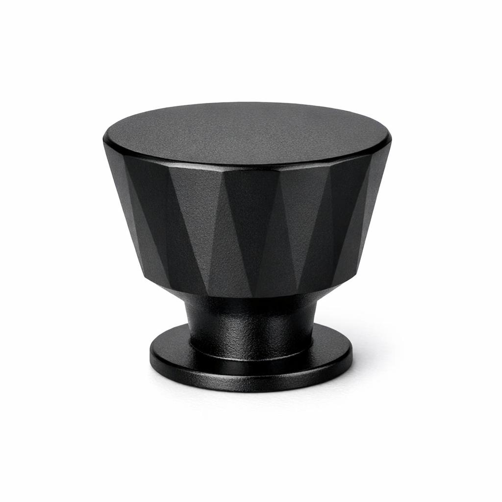 Commercial product photograph. A single residential cabinet knob. Faceted surface texture. Round Knob shape. Matte Black metal finish. Small circular base plate, single mounting post, approximately 1-1/4 inch diameter. Photographed on pure white seamless background (#FFFFFF). Studio softbox lighting, soft shadow directly underneath only. Macro lens, sharp focus throughout. Photorealistic real metal hardware. Not a 3D render. Not an illustration. Not CGI. Real cabinet hardware product photography quality. Variation 8: Select Conical style cabinet knob: an inverted truncated cone cut into faceted flat planes around the tapered surface, wide flat top, narrow base..
