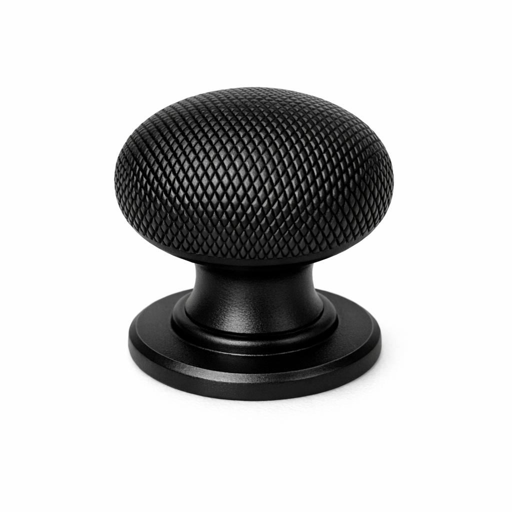Commercial product photograph. A single residential cabinet knob. Knurled surface texture. Round Knob shape. Matte Black metal finish. Small circular base plate, single mounting post, approximately 1-1/4 inch diameter. Photographed on pure white seamless background (#FFFFFF). Studio softbox lighting, soft shadow directly underneath only. Macro lens, sharp focus throughout. Photorealistic real metal hardware. Not a 3D render. Not an illustration. Not CGI. Real cabinet hardware product photography quality. Variation 1: Providence style cabinet knob: classic mushroom dome top, fine diamond crosshatch knurling across the entire dome, short thick neck, wide circular base plate with beveled edge. 1-1/4 inch diameter..