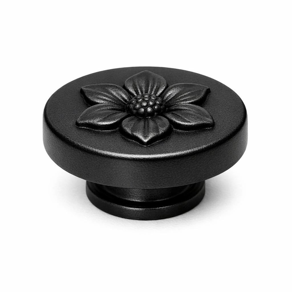 Commercial product photograph. A single residential cabinet knob. Floral surface texture. Round Knob shape. Matte Black metal finish. Small circular base plate, single mounting post, approximately 1-1/4 inch diameter. Photographed on pure white seamless background (#FFFFFF). Studio softbox lighting, soft shadow directly underneath only. Macro lens, sharp focus throughout. Photorealistic real metal hardware. Not a 3D render. Not an illustration. Not CGI. Real cabinet hardware product photography quality. Variation 2: Paxton style cabinet knob: flat low puck with a single raised flower blossom relief centered on the top face, straight sides, thin base ring..