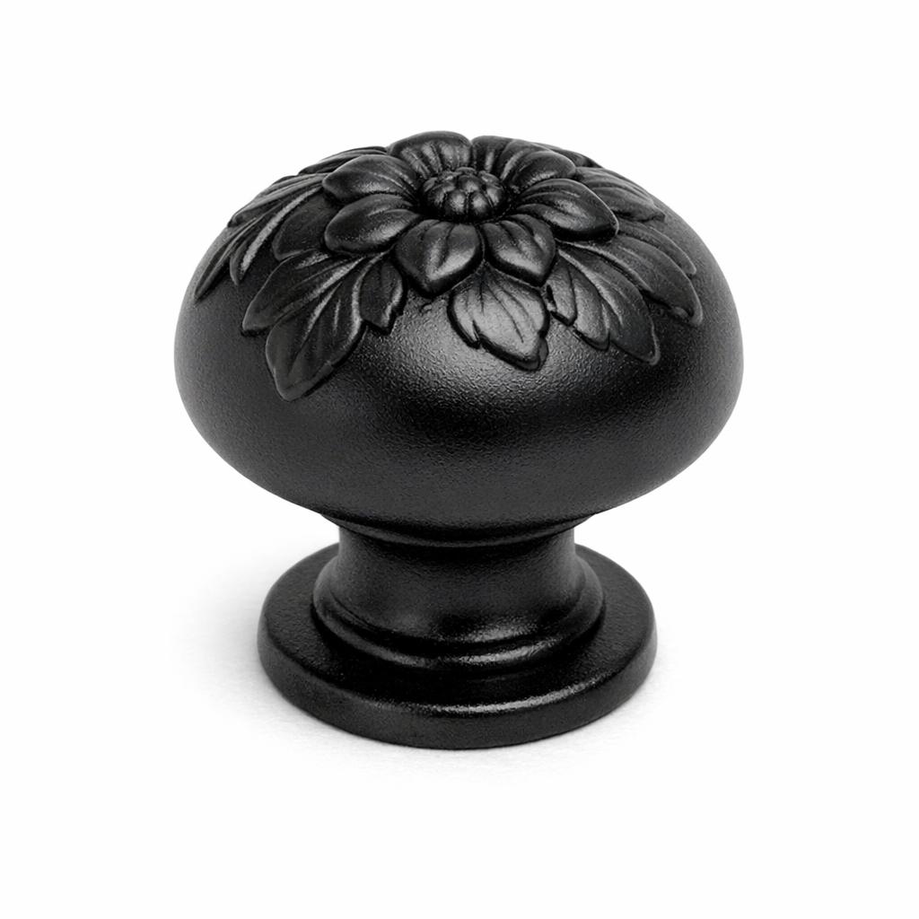 Commercial product photograph. A single residential cabinet knob. Floral surface texture. Round Knob shape. Matte Black metal finish. Small circular base plate, single mounting post, approximately 1-1/4 inch diameter. Photographed on pure white seamless background (#FFFFFF). Studio softbox lighting, soft shadow directly underneath only. Macro lens, sharp focus throughout. Photorealistic real metal hardware. Not a 3D render. Not an illustration. Not CGI. Real cabinet hardware product photography quality. Variation 1: Providence style cabinet knob: tall mushroom dome with raised floral relief, sculpted flower petals and leaves wrapping the dome, short thick neck, small circular base plate..