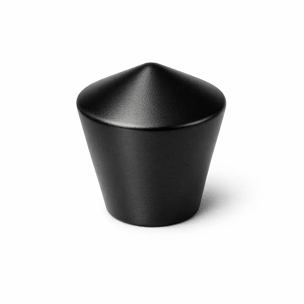 Commercial product photograph. A single residential cabinet knob. Smooth surface texture. Round Knob shape. Matte Black metal finish. Small circular base plate, single mounting post, approximately 1-1/4 inch diameter. Photographed on pure white seamless background (#FFFFFF). Studio softbox lighting, soft shadow directly underneath only. Macro lens, sharp focus throughout. Photorealistic real metal hardware. Not a 3D render. Not an illustration. Not CGI. Real cabinet hardware product photography quality. Variation 6: Cone knob: tapered cone shape, pointed or rounded top, wider at base, no separate base plate. Geometric modern style..