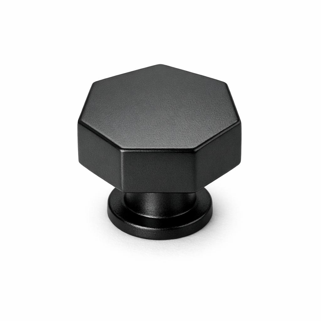 Commercial product photograph. A single residential cabinet knob. Smooth surface texture. Round Knob shape. Matte Black metal finish. Small circular base plate, single mounting post, approximately 1-1/4 inch diameter. Photographed on pure white seamless background (#FFFFFF). Studio softbox lighting, soft shadow directly underneath only. Macro lens, sharp focus throughout. Photorealistic real metal hardware. Not a 3D render. Not an illustration. Not CGI. Real cabinet hardware product photography quality. Variation 9: Hexagonal knob: six-sided geometric hex shape, flat top face, angular sides, small base. Modern geometric style..
