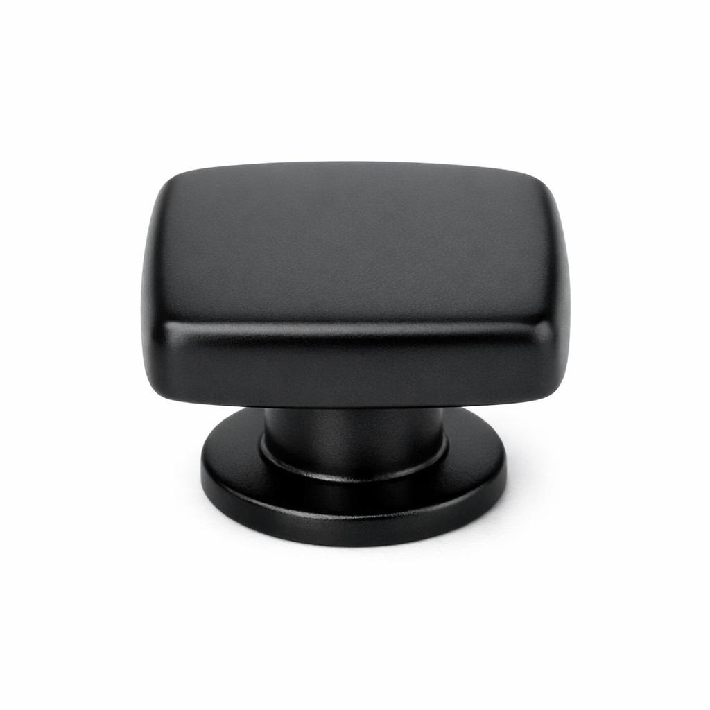 Commercial product photograph. A single residential cabinet knob. Smooth surface texture. Round Knob shape. Matte Black metal finish. Small circular base plate, single mounting post, approximately 1-1/4 inch diameter. Photographed on pure white seamless background (#FFFFFF). Studio softbox lighting, soft shadow directly underneath only. Macro lens, sharp focus throughout. Photorealistic real metal hardware. Not a 3D render. Not an illustration. Not CGI. Real cabinet hardware product photography quality. Variation 1: Providence style cabinet knob: a square knob with softly rounded edges and corners, a rounded-cube form wider and flatter than a true cube, flat top face, sitting on a small circular base. Smooth surface, no texture, no ribbing, no decorative details..