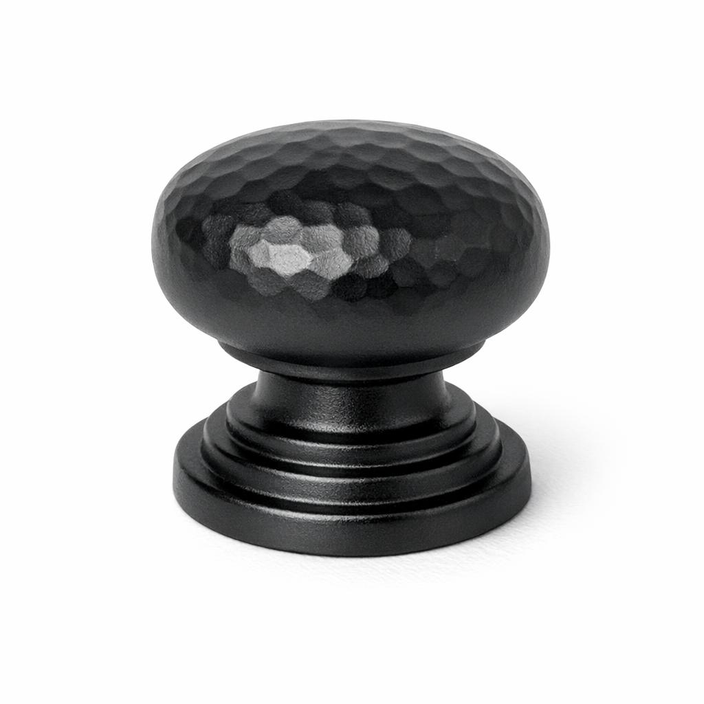 Commercial product photograph. A single residential cabinet knob. Hammered surface texture. Round Knob shape. Matte Blac