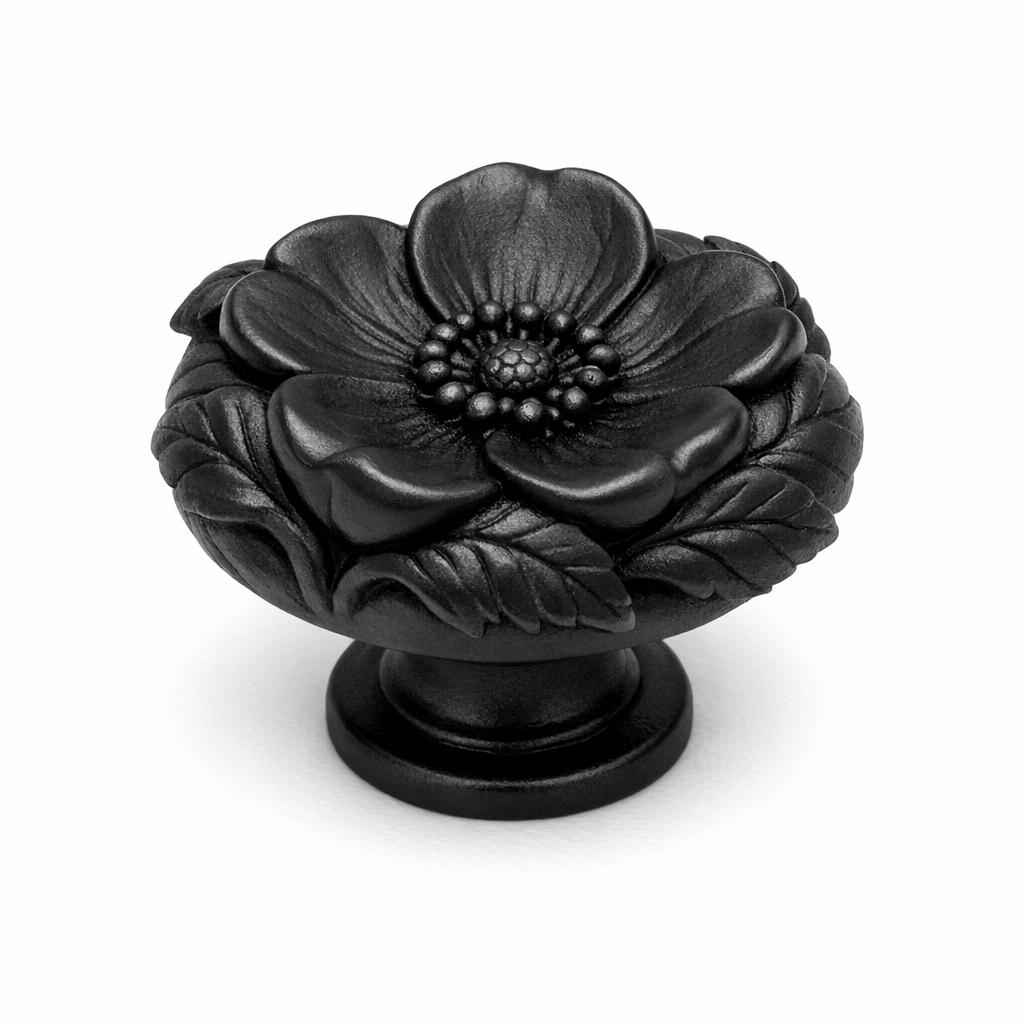 Commercial product photograph. A single residential cabinet knob. Floral surface texture. Round Knob shape. Matte Black metal finish. Small circular base plate, single mounting post, approximately 1-1/4 inch diameter. Photographed on pure white seamless background (#FFFFFF). Studio softbox lighting, soft shadow directly underneath only. Macro lens, sharp focus throughout. Photorealistic real metal hardware. Not a 3D render. Not an illustration. Not CGI. Real cabinet hardware product photography quality. Variation 6: Cabinet knob sculpted as a wild rose surrounded by sculpted leaves, an open five-petal flower with dimensional leaves curling around the sides, deep relief, small round base. Cast metal floral hardware..