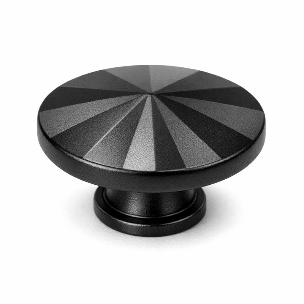 Commercial product photograph. A single residential cabinet knob. Faceted surface texture. Round Knob shape. Matte Black metal finish. Small circular base plate, single mounting post, approximately 1-1/4 inch diameter. Photographed on pure white seamless background (#FFFFFF). Studio softbox lighting, soft shadow directly underneath only. Macro lens, sharp focus throughout. Photorealistic real metal hardware. Not a 3D render. Not an illustration. Not CGI. Real cabinet hardware product photography quality. Variation 7: Rustic Modern style cabinet knob: a wide shallow disc cut into radial faceted wedges fanning from the center across the top face, thin base ring..